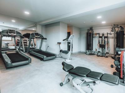 Moderner Fitnessraum mit Laufbändern, Ergometer und Kraftgeräten, heller Raum mit grauem Boden.