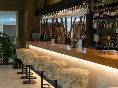 Moderne bar met bloemenpatroon barkrukken en verlichte houten toonbank.