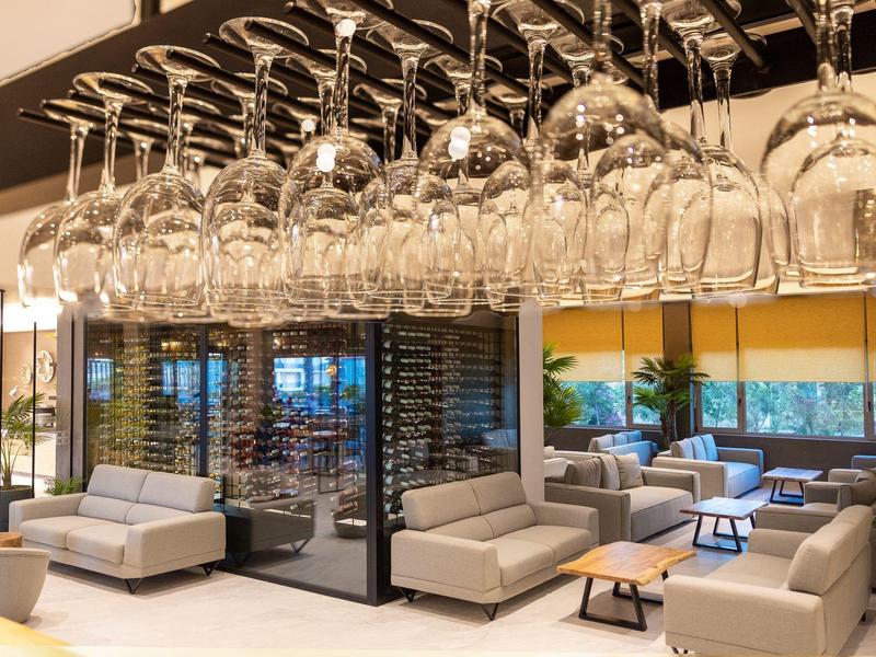 Salón de hotel moderno con copas de vino colgadas sobre sofás y mesas cómodas.