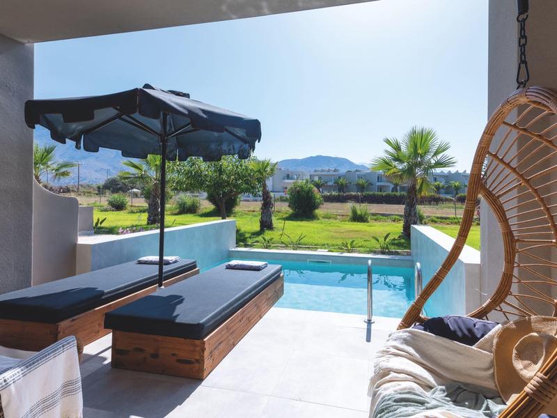 Terraza con piscina, tumbonas y silla colgante con vistas a paisaje verde y montañas.