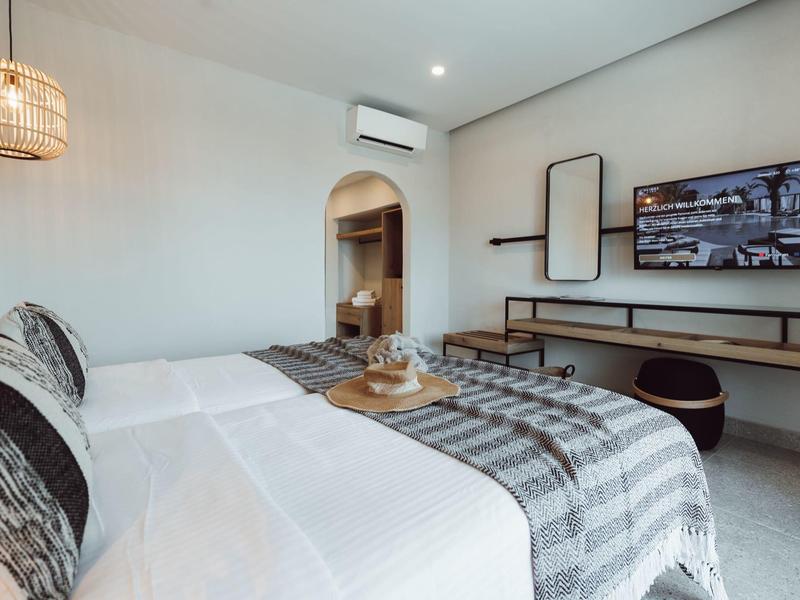 Habitación de hotel moderna con cama doble, televisor plano y decoración sencilla.