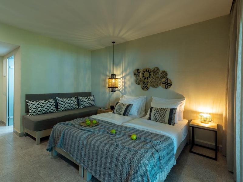 Acogedora habitación de hotel con cama doble, área de sofá e iluminación suave por la noche.