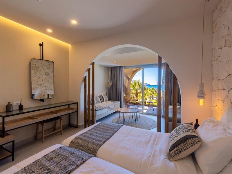 Habitación de hotel con dos camas, decoración moderna y balcón con vistas al mar.