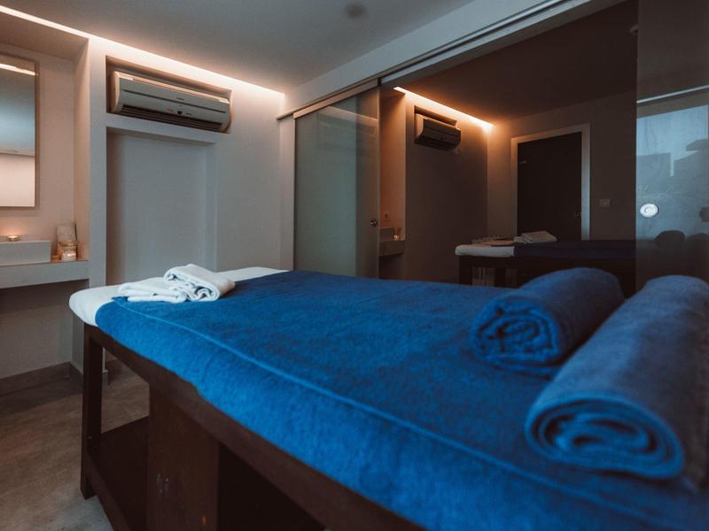 Sala de masajes moderna con toalla azul y iluminación tenue.