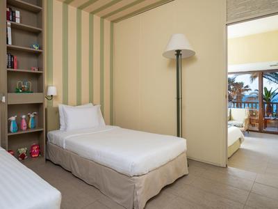 Hotelzimmer mit zwei Einzelbetten, Bücherregal und Blick auf Balkon und Meer