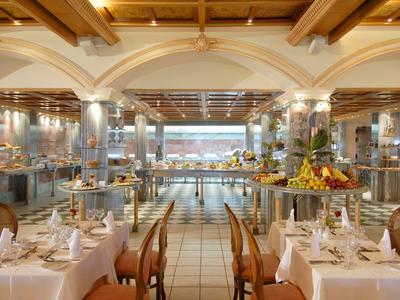 Modernes Hotelgebäude mit Balkonzimmern und Parkanlage im Vordergrund bei Sonnenschein.