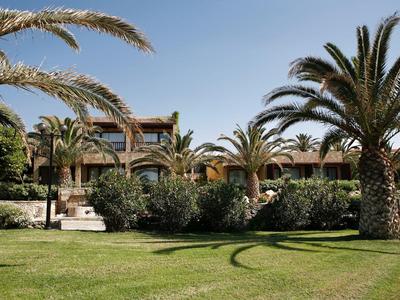 Hotelgebäude mit Palmen und gepflegtem Rasen im Vordergrund unter klarem Himmel