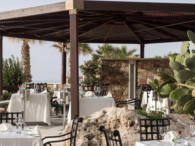 Elegantes Außenrestaurant mit weißen Tischtüchern und Pflanzen in sonnigem Ambiente.