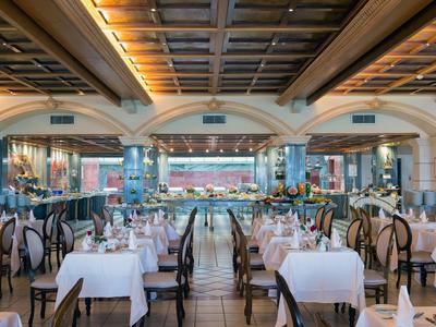 Elegantes Restaurant mit weiß gedeckten Tischen und Holzdecke in einem Hotel.