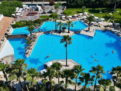 Großer Hotelpool mit Sonnenliegen und Palmen in einem tropischen Resort