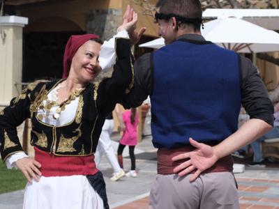 Ein Paar in traditioneller Kleidung tanzt draußen vor einem Gebäude.