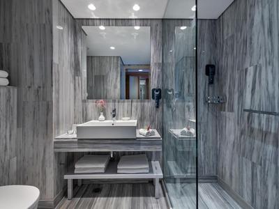 Baño moderno con azulejos imitación madera, ducha abierta y lavabo con espejo.