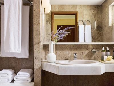 Baño luminoso con toalla blanca y artículos de aseo organizados junto al lavabo.