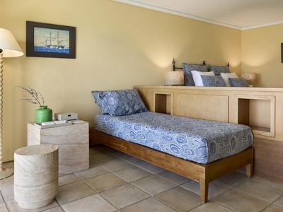 Habitación de hotel luminosa con cama doble, tumbona separada y lámpara de pie moderna.
