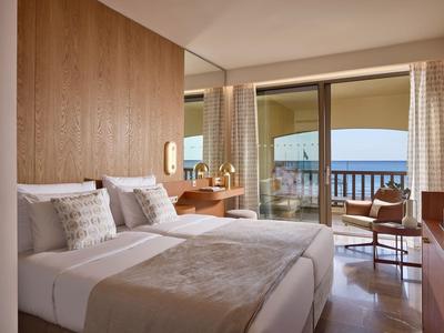 Habitación de hotel moderna con dos camas individuales y balcón con vista al mar.