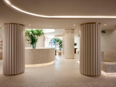 Elegante vestíbulo de hotel con columnas redondas, tonos blancos y iluminación moderna.