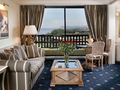 Elegantes Wohnzimmer mit Sofa, Sesseln, Holztisch und Aussicht auf Balkon und Berge.