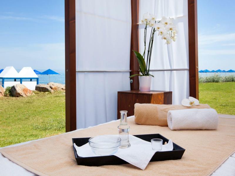 Entspannender Bereich im Freien mit Liegestuhl, Wasserflasche und Blick auf Zelte am Meer