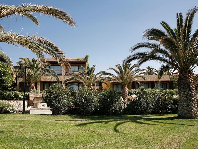 Hotelgebäude mit Garten und Palmen unter klarem Himmel