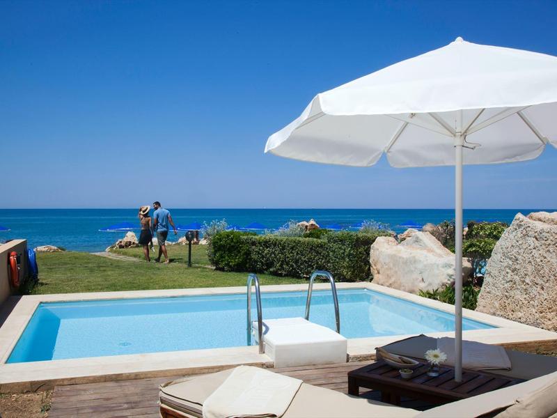 Pool mit weißem Sonnenschirm und Meerblick an einem sonnigen Tag