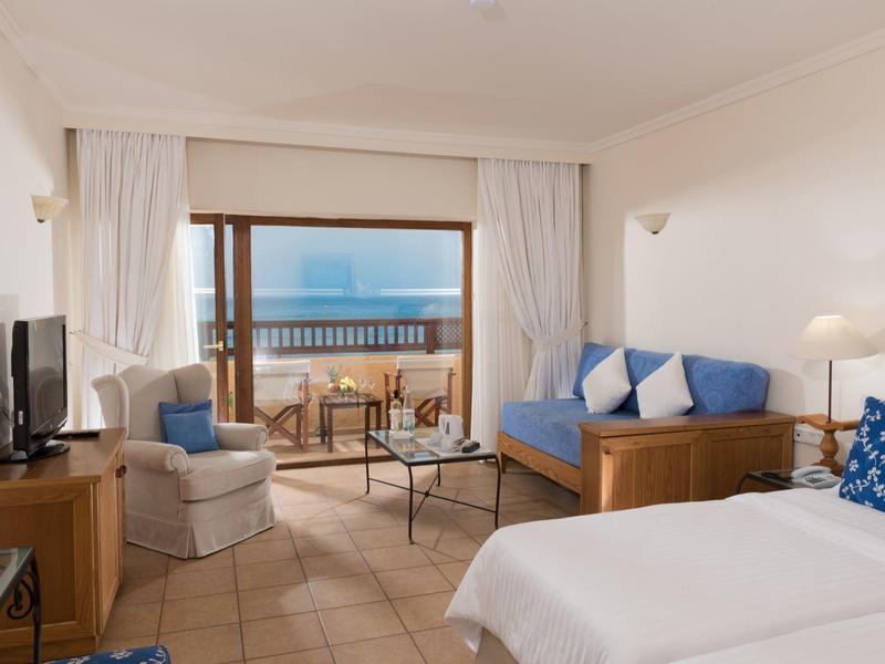 Gemütliches Hotelzimmer mit Balkon, Meerblick, Sitzecke und Bett.