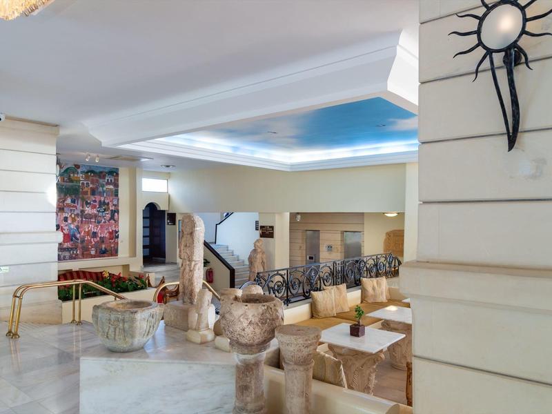 Helle Hotellobby mit moderner Möblierung, kunstvoller Wanddeko und großer Sitzgruppe.