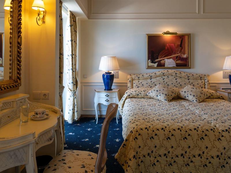 Gemütliches Hotelzimmer mit Doppelbett, Nachttischen und einem Schminktisch mit Spiegel.