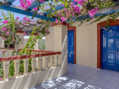 Balcony with blooming bougainvillea plants and blue doors on a sunny day.