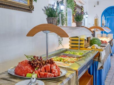 Buffet con frutta fresca e insalate in una stanza luminosa con porte blu
