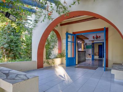 Un arco luminoso con porte blu si apre su un interno con piante in un hotel.
