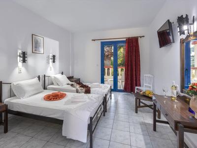 Bright hotel room with two beds, flat-screen TV, and balcony with red curtain.