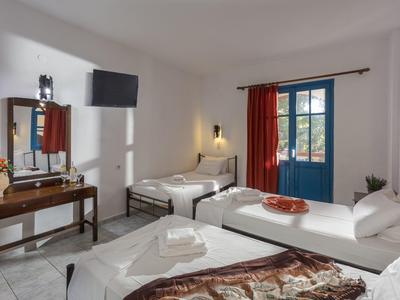 Camera d'hotel luminosa con due letti singoli, finestra con tenda rossa e TV a muro.