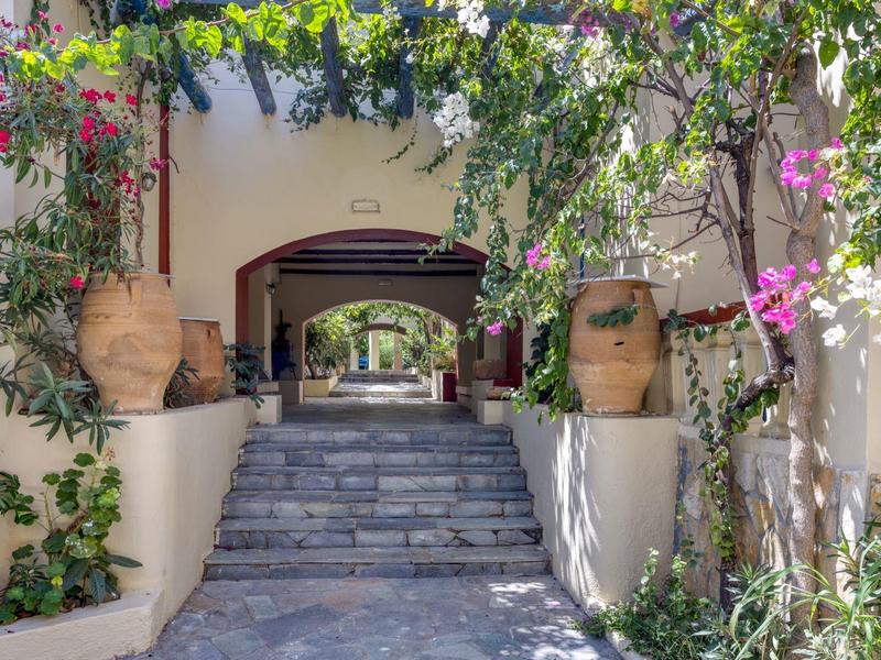 Ingresso con scale, grandi vasi e piante fiorite lungo i muri.