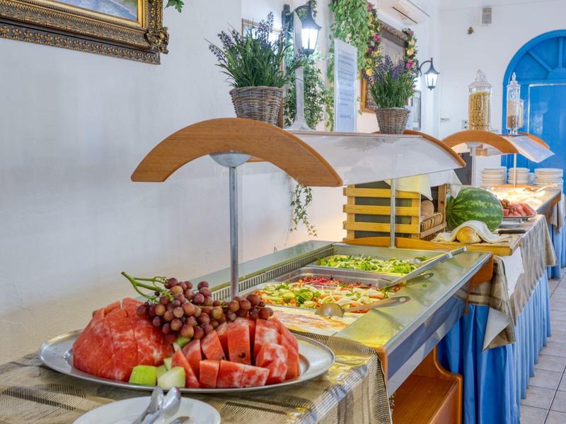 Buffet con frutta fresca e insalate in una stanza luminosa con porte blu