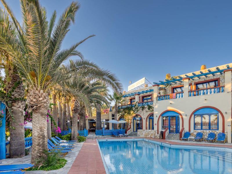 Hotel con piscina all'aperto circondata da palme e cielo blu