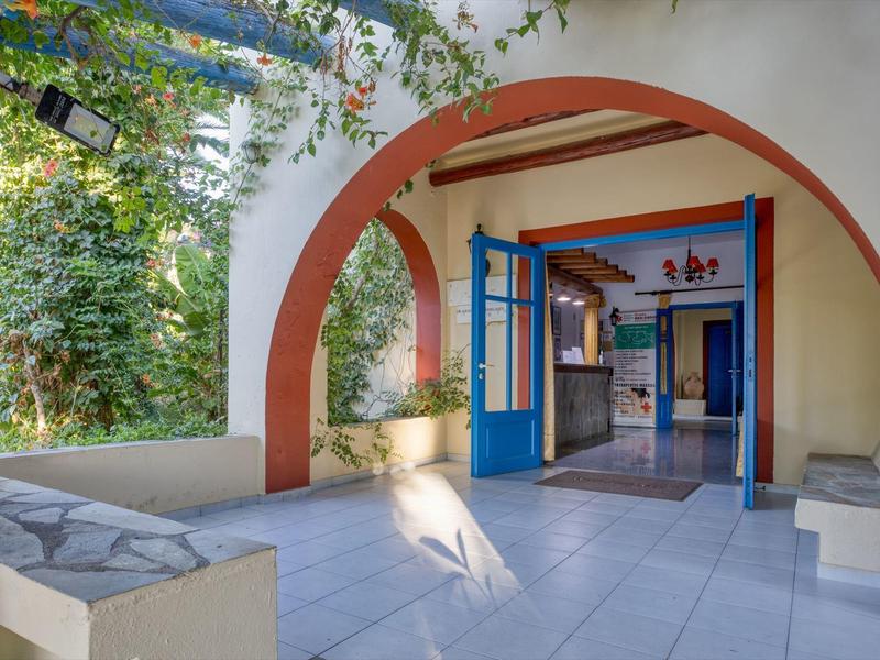 Un arco luminoso con porte blu si apre su un interno con piante in un hotel.