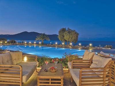 Pohodlná sezení u osvětleného bazénu s výhledem na moře za soumraku.