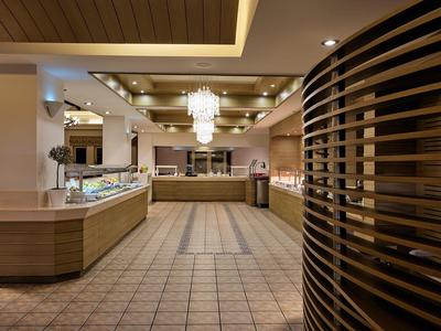 Luxusní hotelová lobby s lustry a moderním dřevěným detailem napravo.