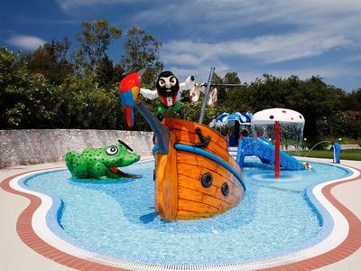 Barevné dětské vodní hřiště s lodí v bazénu.