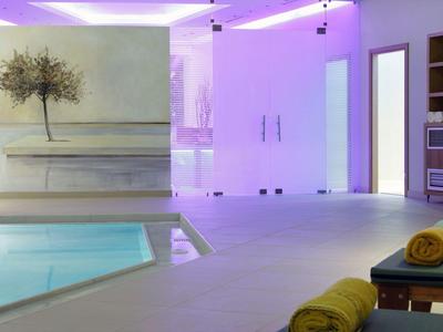 Moderní wellness prostor s bazénem, lehátky a příjemným osvětlením.