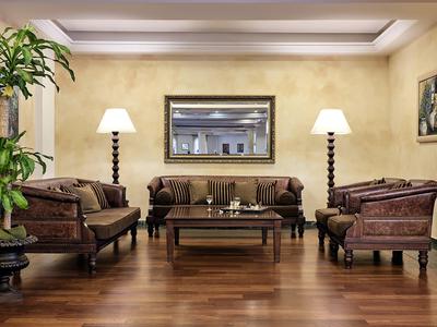 Elegantní hotelový salonek s koženými křesly, dřevěným stolem a teplým osvětlením lamp.