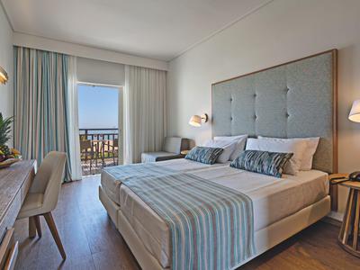 Modernes Hotelzimmer mit Doppelbett, Sitzbereich und Balkon mit Meerblick.