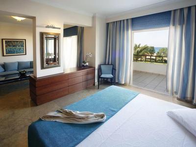 Hotelový pokoj s postelí, modrými závěsy, balkonem a sedací soupravou.