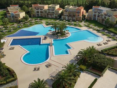 Blick auf eine Hotelanlage mit mehreren Pools und umliegenden Bungalows in einer grünen Umgebung.