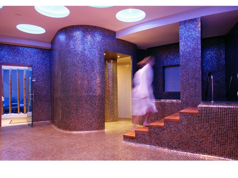 Moderní wellness s mozaikovými dlaždicemi, schody a relaxační atmosférou.