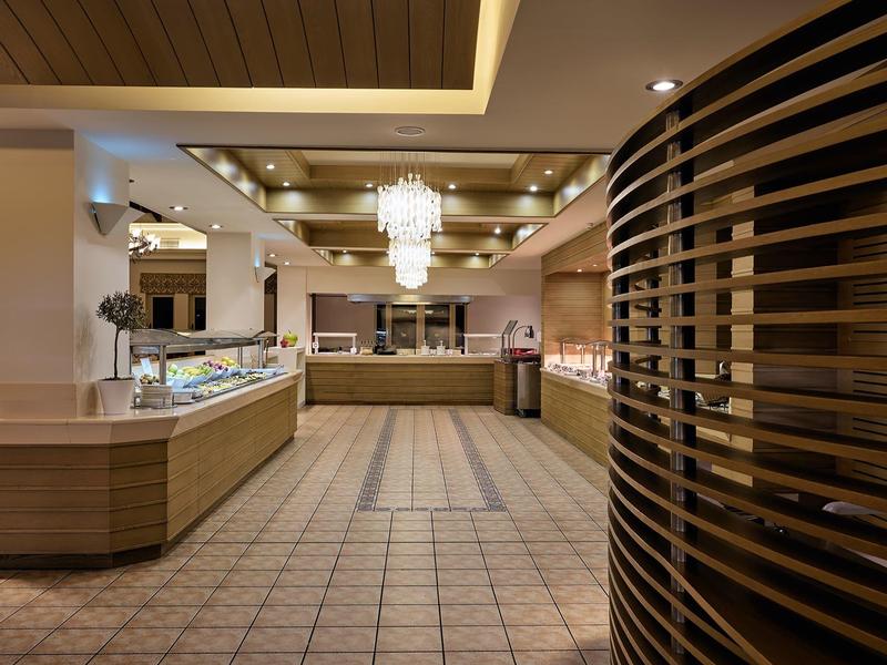 Luxusní hotelová lobby s lustry a moderním dřevěným detailem napravo.