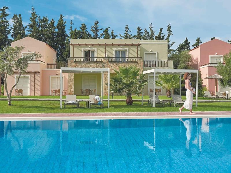 Moderní bazén před řadovými bungalovy s terasami a zahradami za jasného počasí.