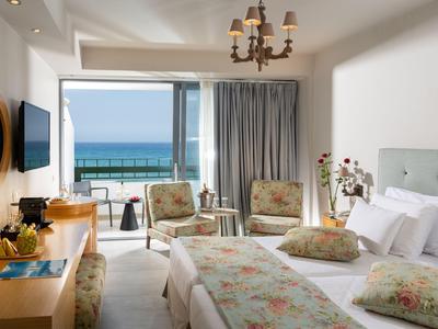 Chambre d'hôtel lumineuse avec lit double et balcon avec vue sur la mer.