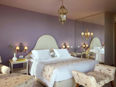 Gemütliches Hotelzimmer mit Doppelbett, violetter Wand und sanfter Beleuchtung.