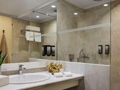 Modernes Badezimmer mit Waschbecken, großem Spiegel und beige Fliesen im Hotel.